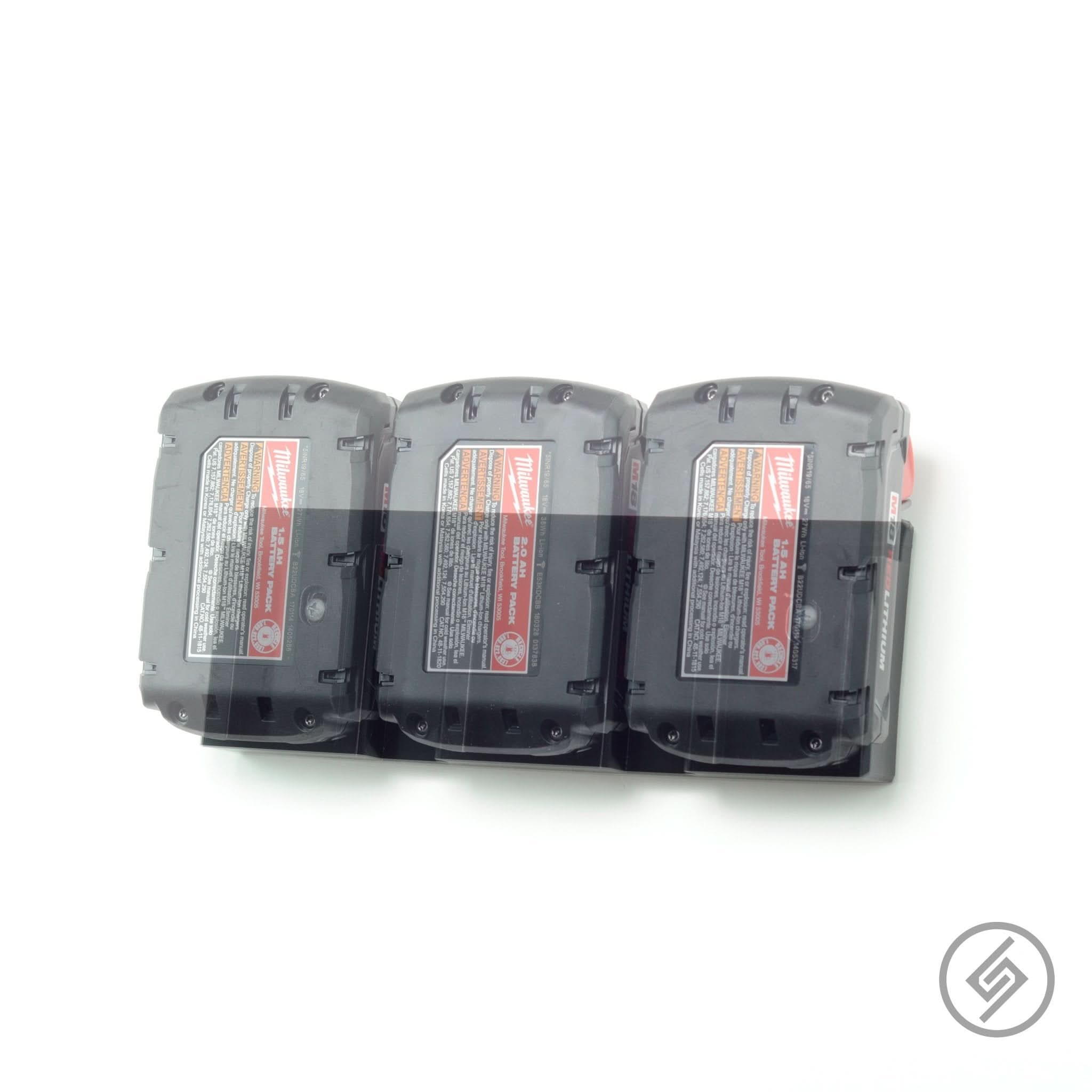 Three Milwaukee M18 batteries shown loaded in the Spartan Mounts wall rack for organized shop storage